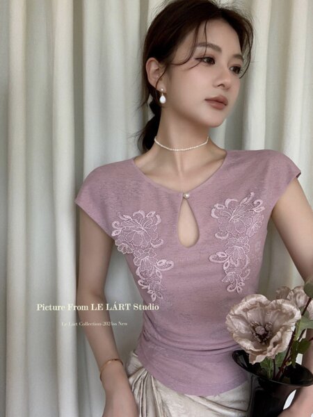 Model wearing a mauve short-sleeve floral lace top with a keyhole neckline