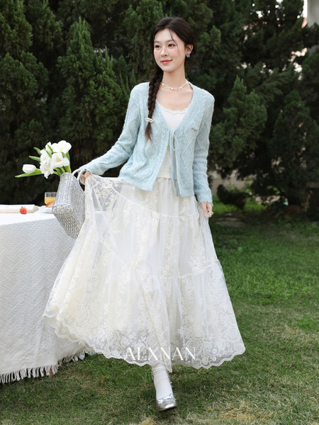 Model wearing a light blue cardigan and white lace skirt outfit outdoors