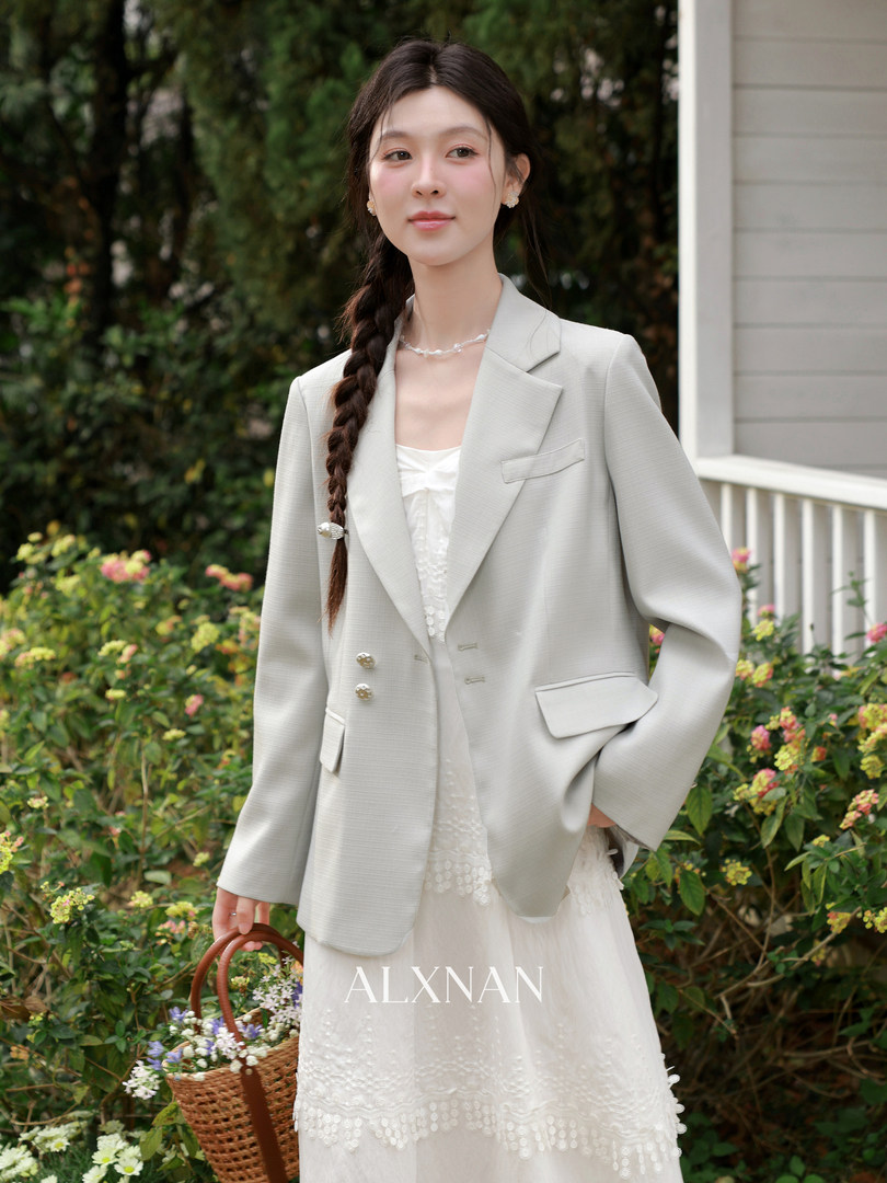Woman modeling a light gray blazer over a white dress outdoors