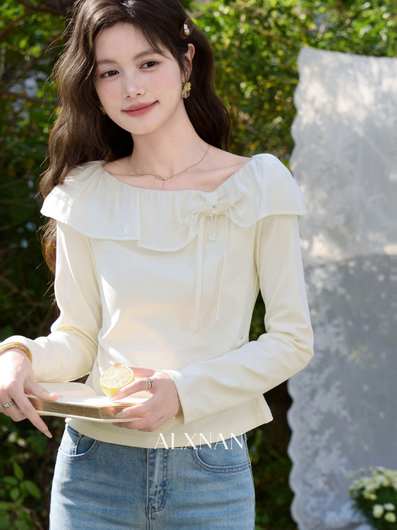 Model wearing a cream long-sleeve ruffled blouse with jeans outdoors