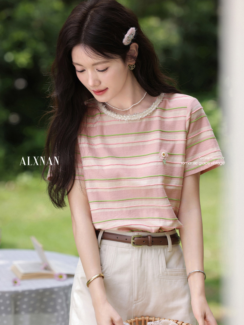 Model wearing a pink striped short-sleeve top with decorative trim and beige pants