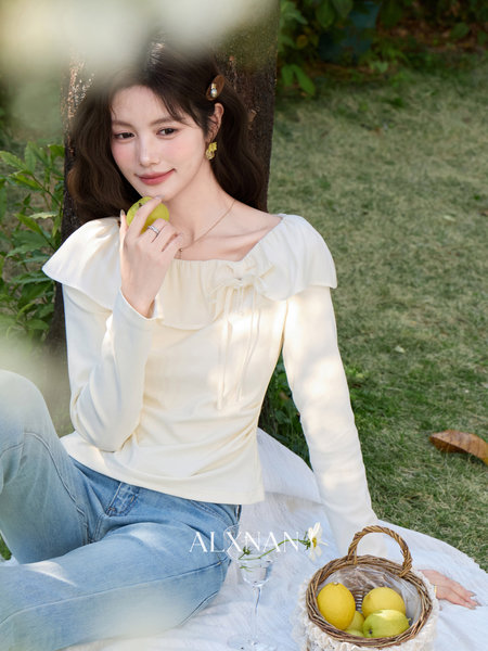 Woman wearing a cream long-sleeve blouse with blue jeans outdoors