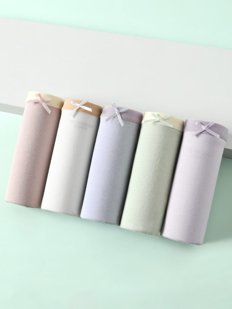 Pastel folded fabric garments with ribbon bows on a light background