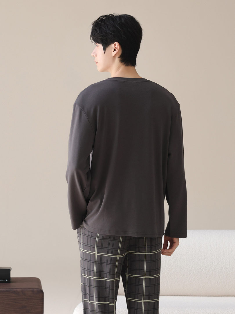 Model wearing a dark long-sleeve loungewear top with plaid pants