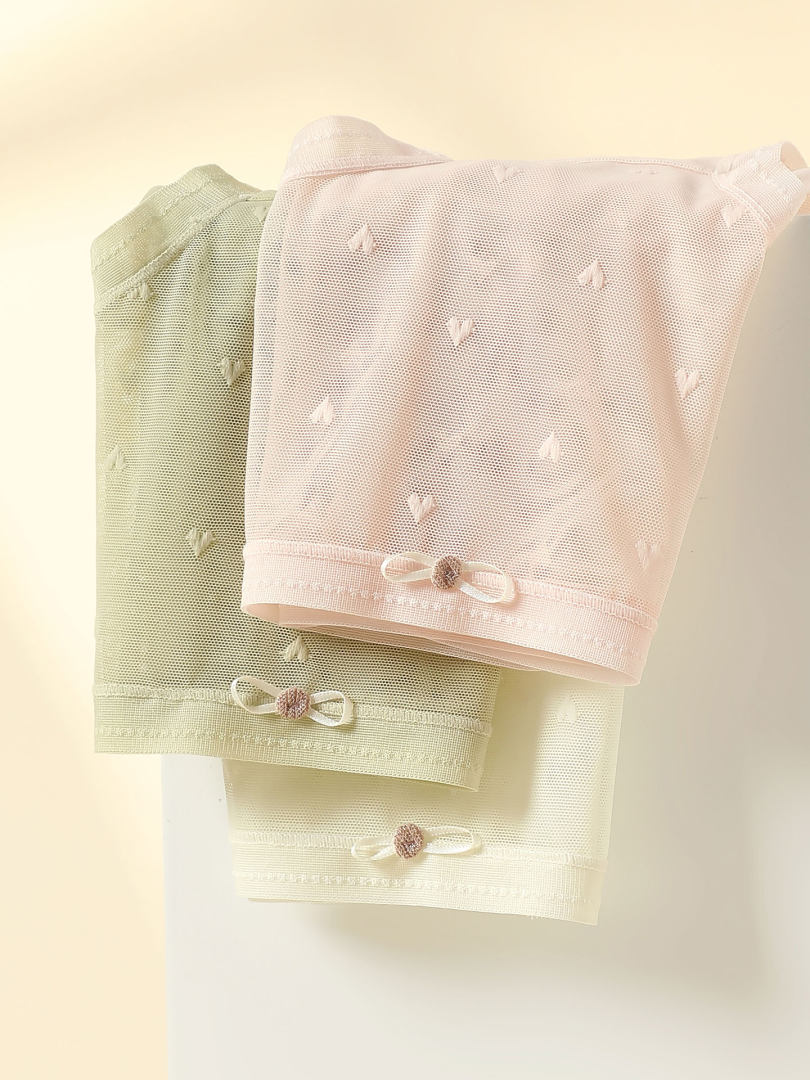 Pastel mesh clothing pieces with small bow accents displayed on a neutral background