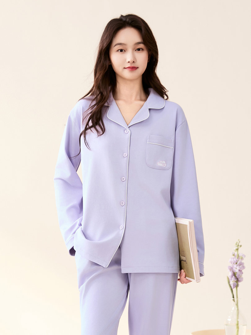 Model wearing a pastel lavender button-up pajama set with long sleeves and matching pants