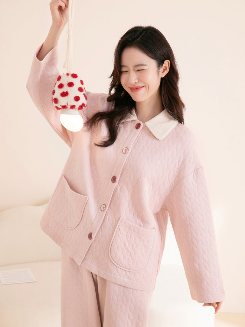 Pink quilted loungewear set worn by a model holding a polka dot plush accessory