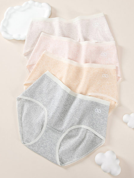 Set of pastel women’s underwear briefs laid flat on a beige background