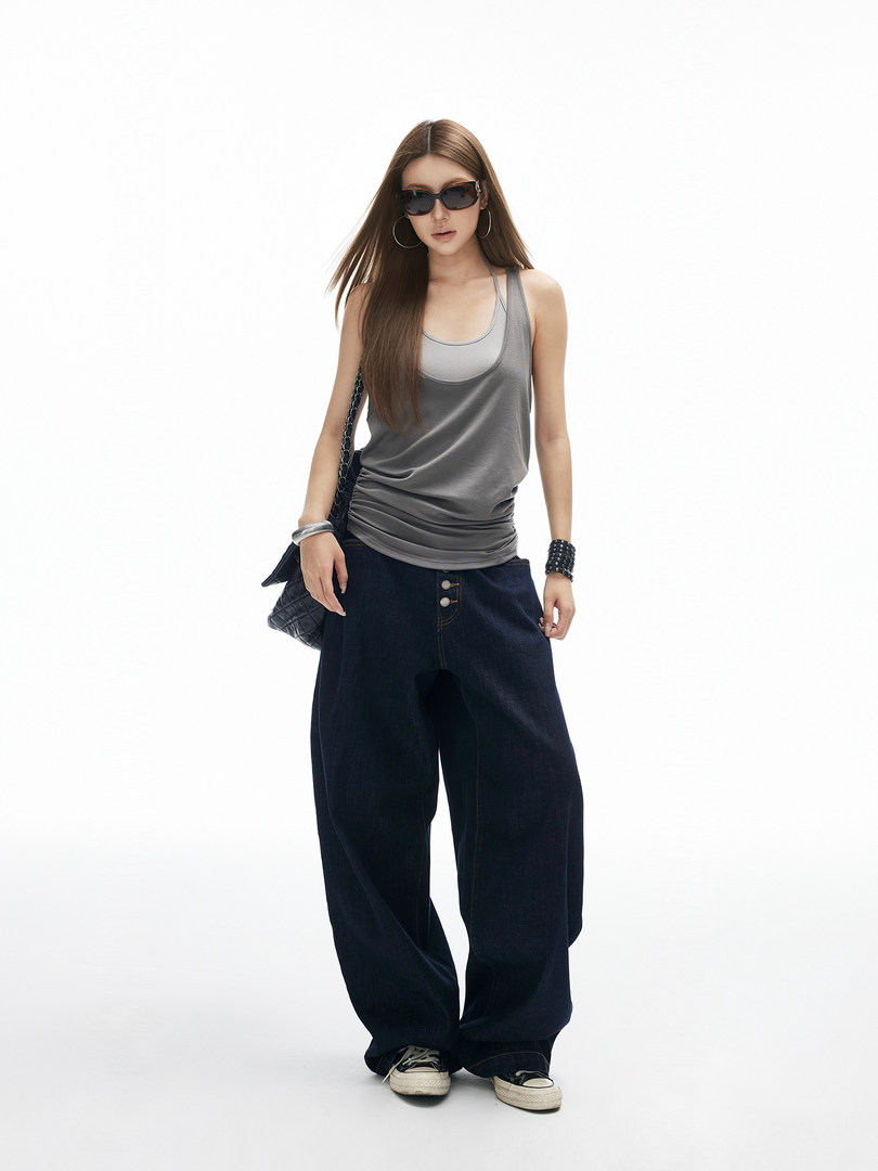 Model wearing a gray tank top with loose dark jeans, sunglasses, and a shoulder bag