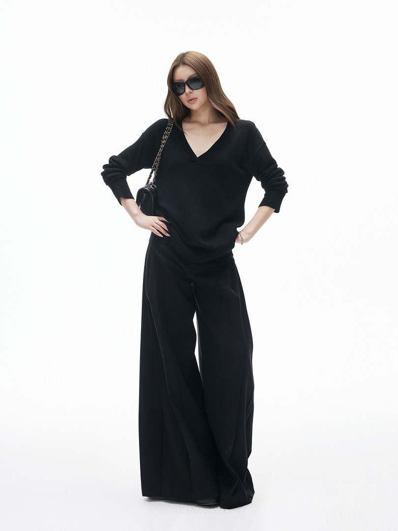Black wide-leg outfit worn by a model with sunglasses and a chain-strap bag