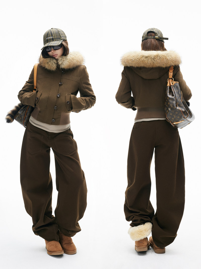 Model wearing a brown fur-collar winter outfit with cap, wide-leg pants, boots, and a shoulder bag