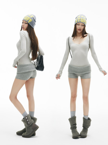 Fashion model wearing a gray knit beanie, bodysuit, shorts, and knit boots