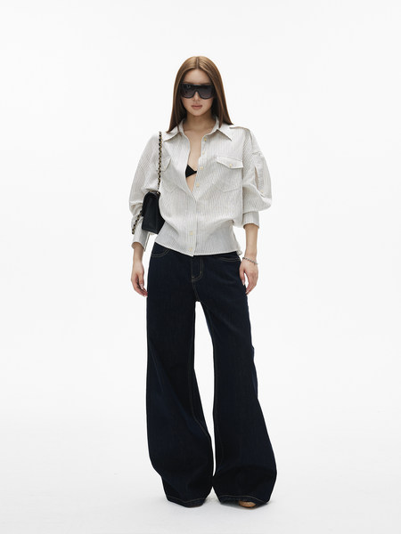 Model wearing a white striped button-up shirt with black wide-leg pants and sunglasses
