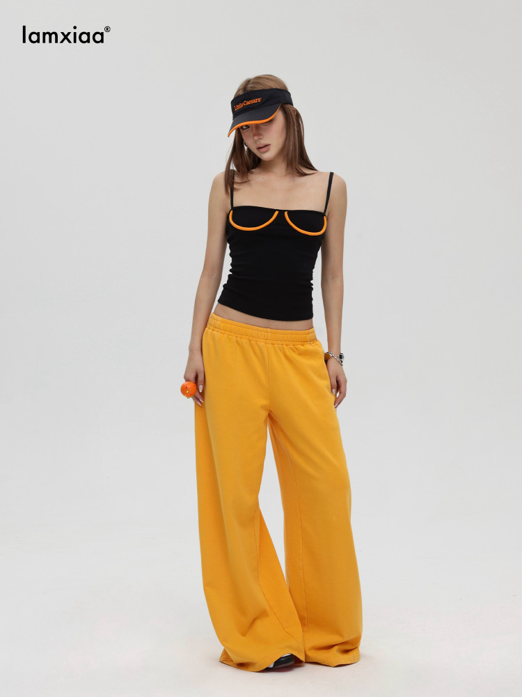 Model wearing a black camisole top with yellow wide-leg pants and a matching visor