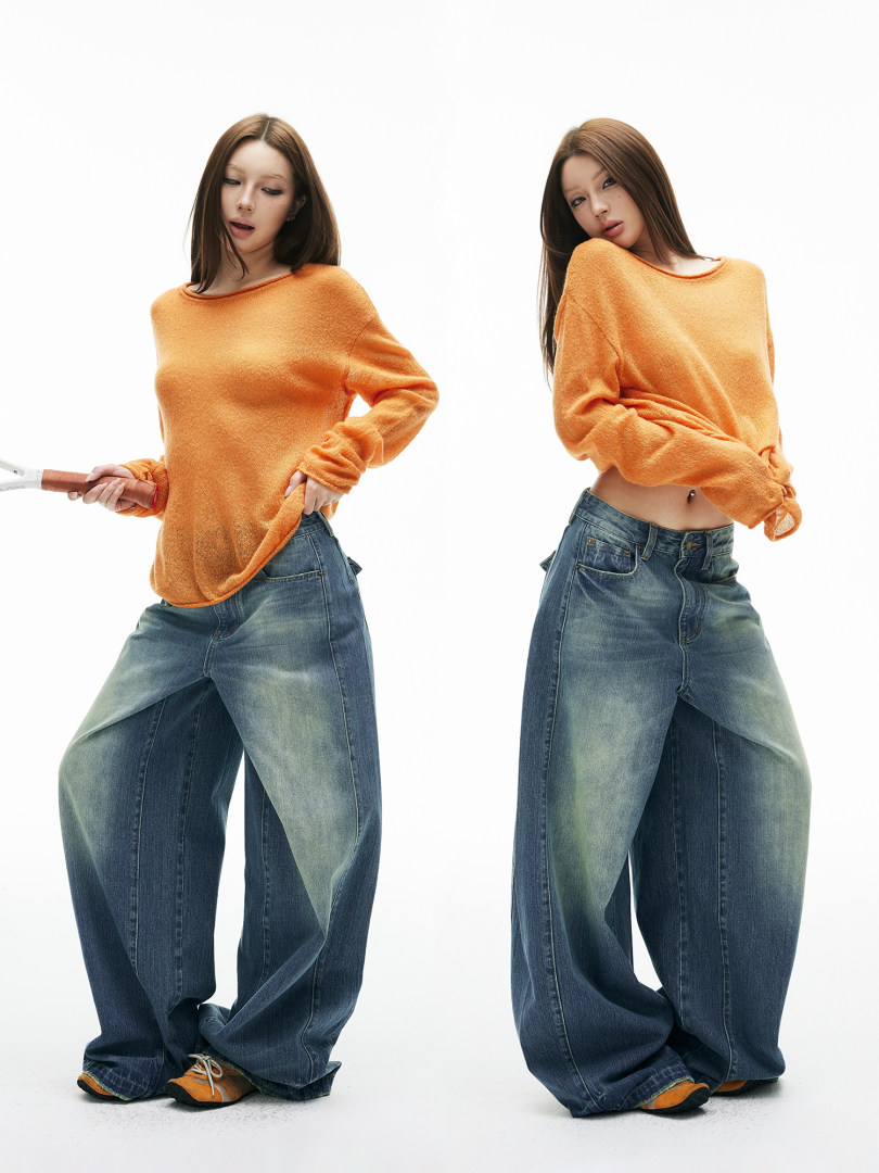 Two models wearing an orange long-sleeve sweater and baggy blue jeans