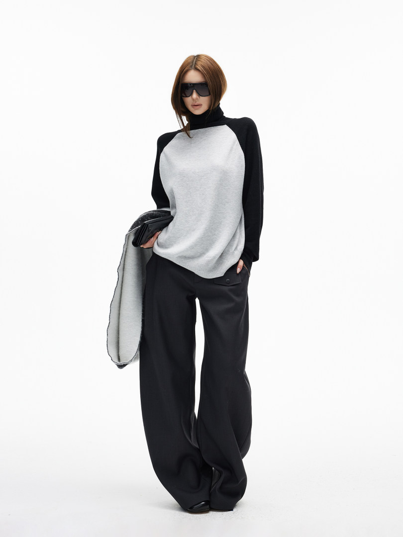 Model wearing a black and gray turtleneck top with wide-leg black pants and sunglasses