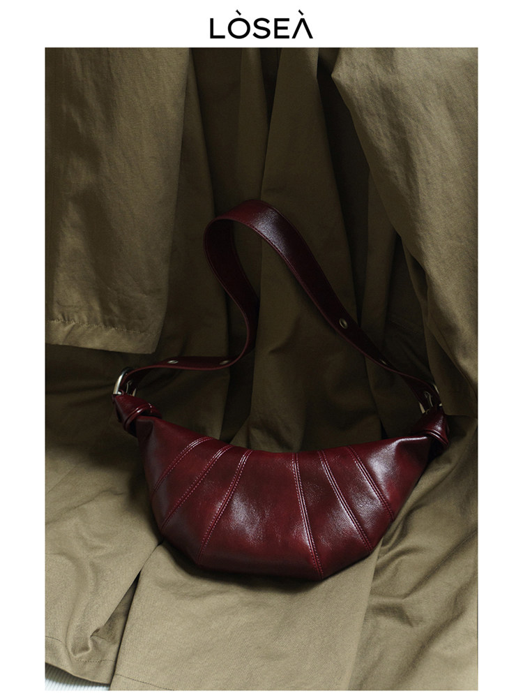 Burgundy leather shoulder bag on a fabric backdrop