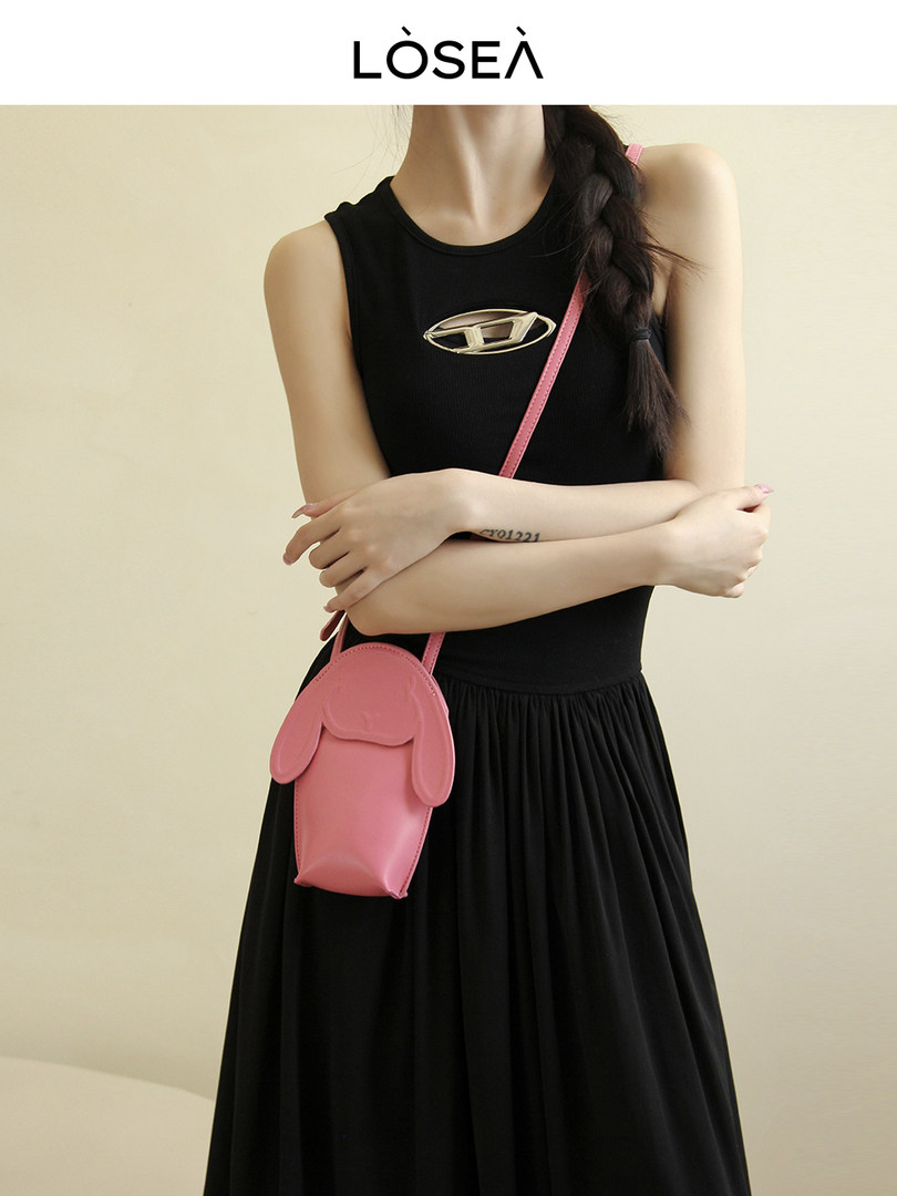 Model wearing a black sleeveless dress with a pink crossbody bag