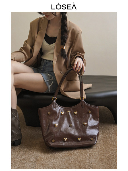 Brown studded leather tote bag shown on a model