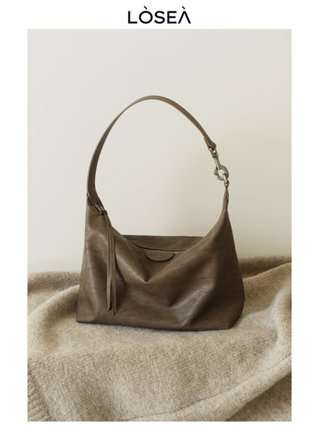 Brown leather shoulder handbag displayed on a neutral background