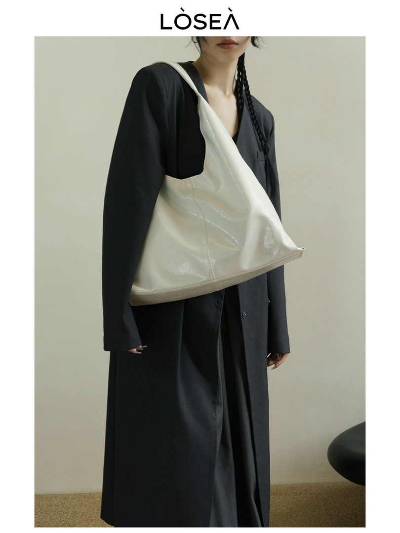White oversized shoulder bag worn by a model with a black coat