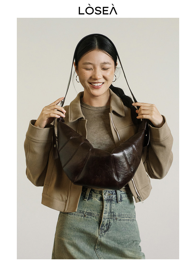 Dark brown leather shoulder bag held by a model