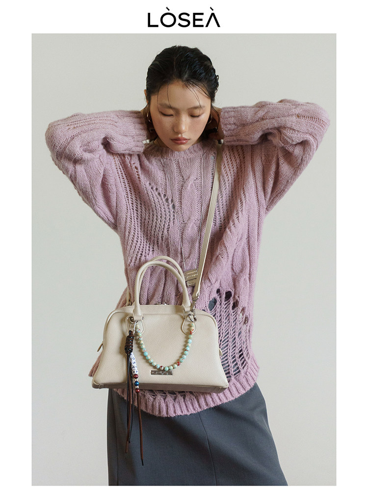 Model wearing a pink oversized knit sweater with a cream handbag