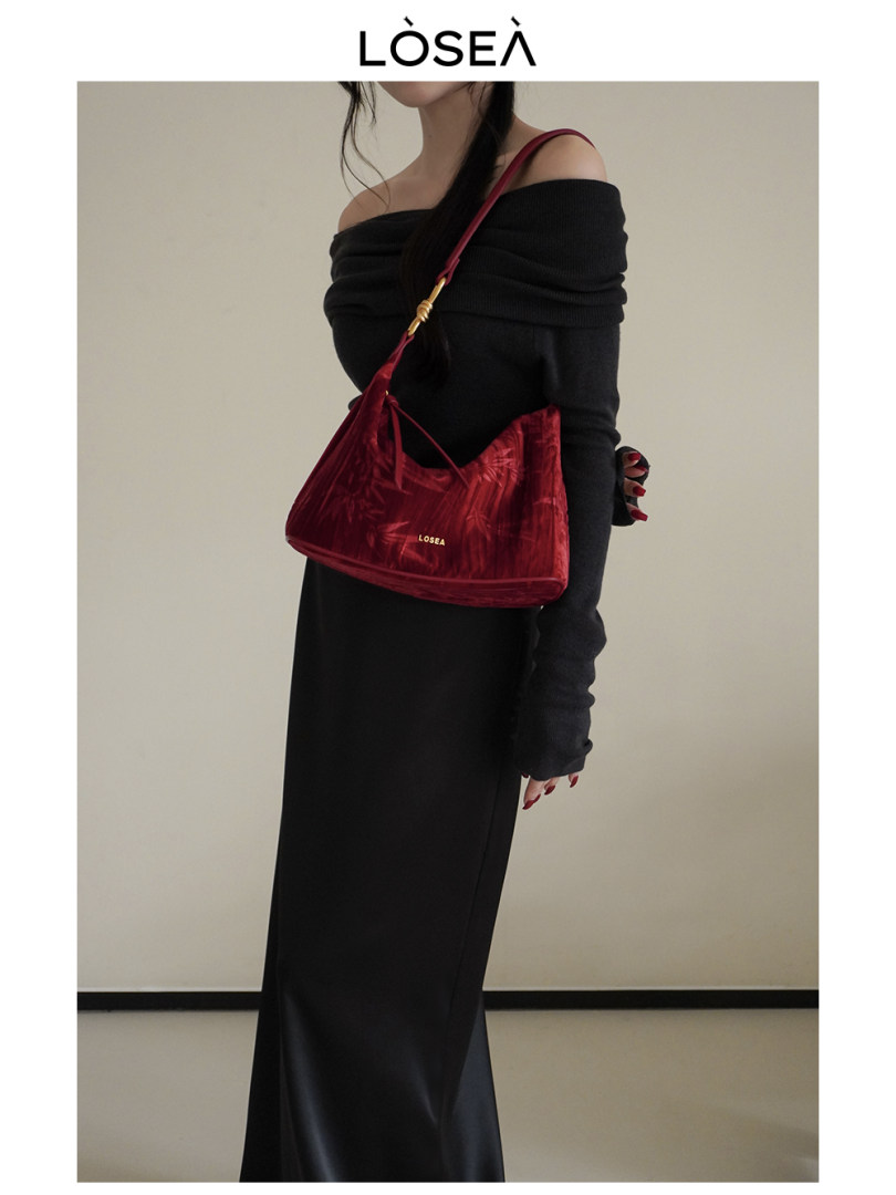 Model wearing a black off-shoulder dress with a red shoulder bag