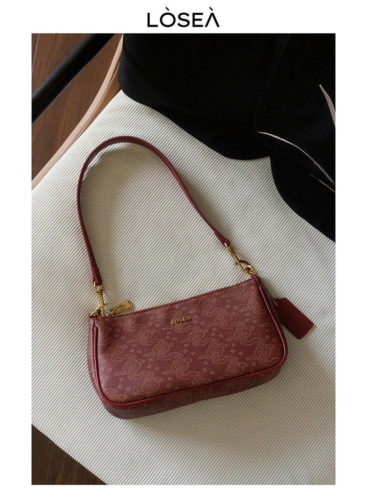 Red leather shoulder handbag on a textured surface