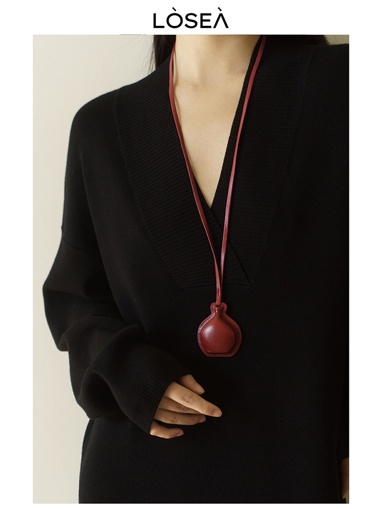 Black long-sleeve knit top worn by a model with a red pendant necklace