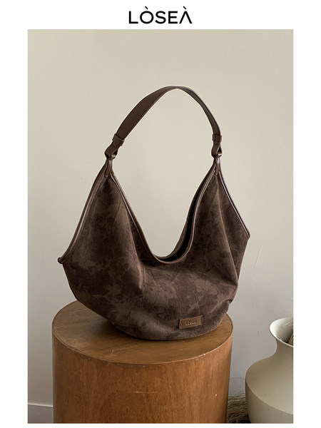 Brown slouchy shoulder bag displayed on a stool