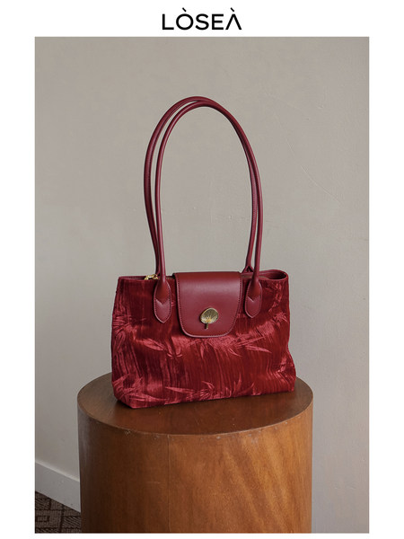 Red velvet handbag with long handles on a pedestal