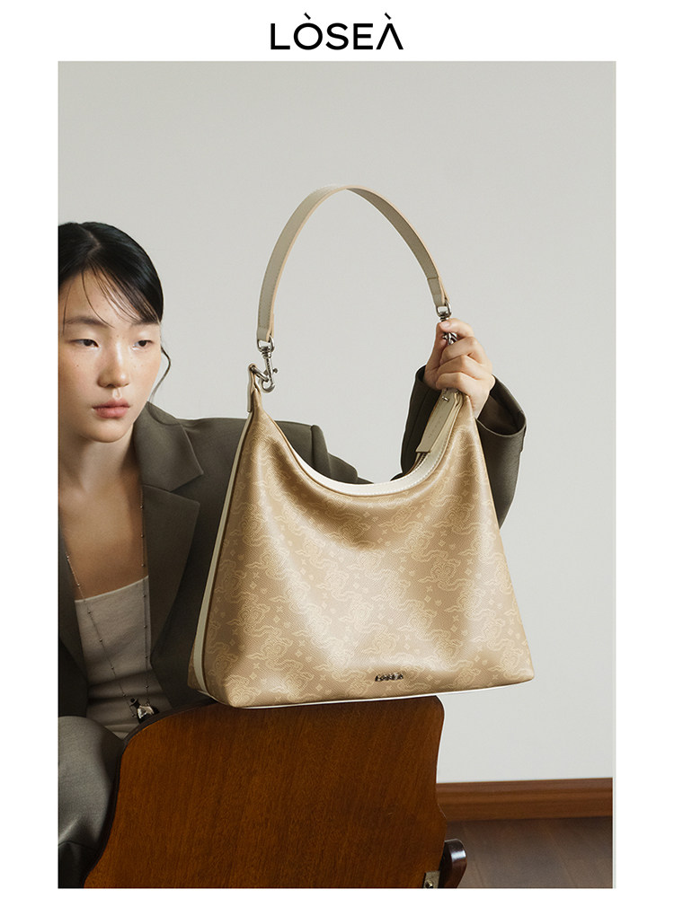 Beige monogram shoulder handbag held by a model