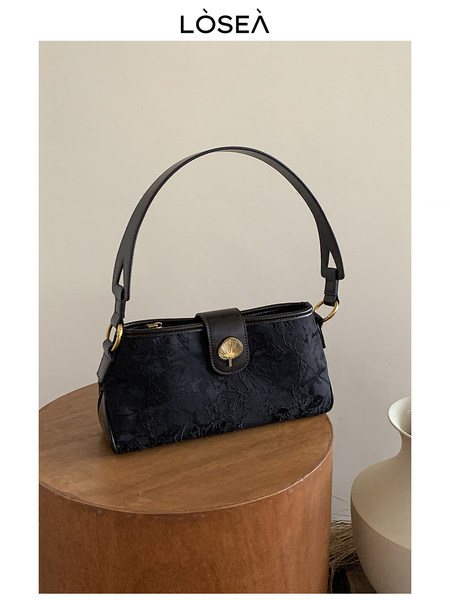 Black shoulder handbag with gold hardware on a table