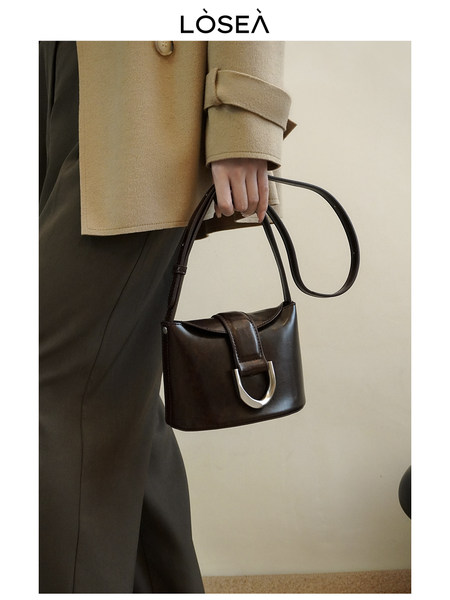 Black leather shoulder handbag held by a model