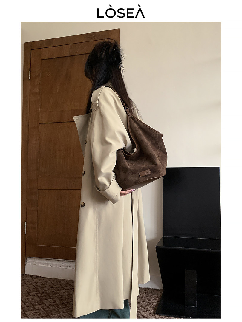 Woman wearing a beige long coat and carrying a brown shoulder bag
