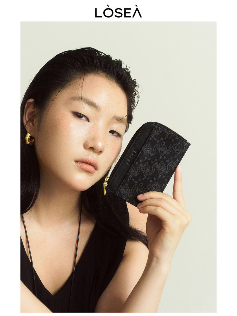 Black patterned wallet or card holder held by a model