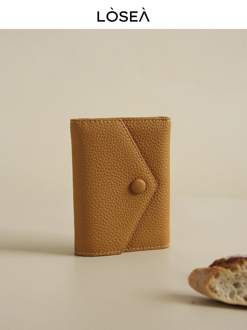 Tan textured leather wallet standing upright on a neutral background