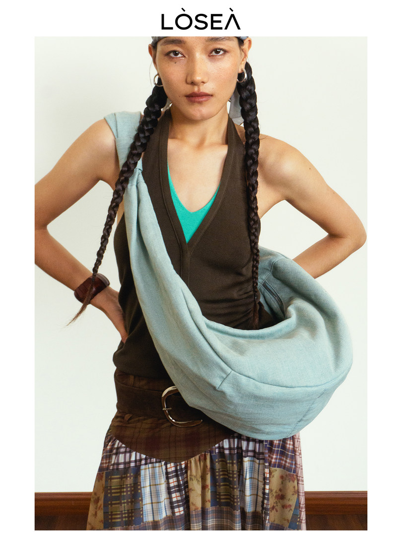 Model wearing a large light blue shoulder bag with layered fashion styling
