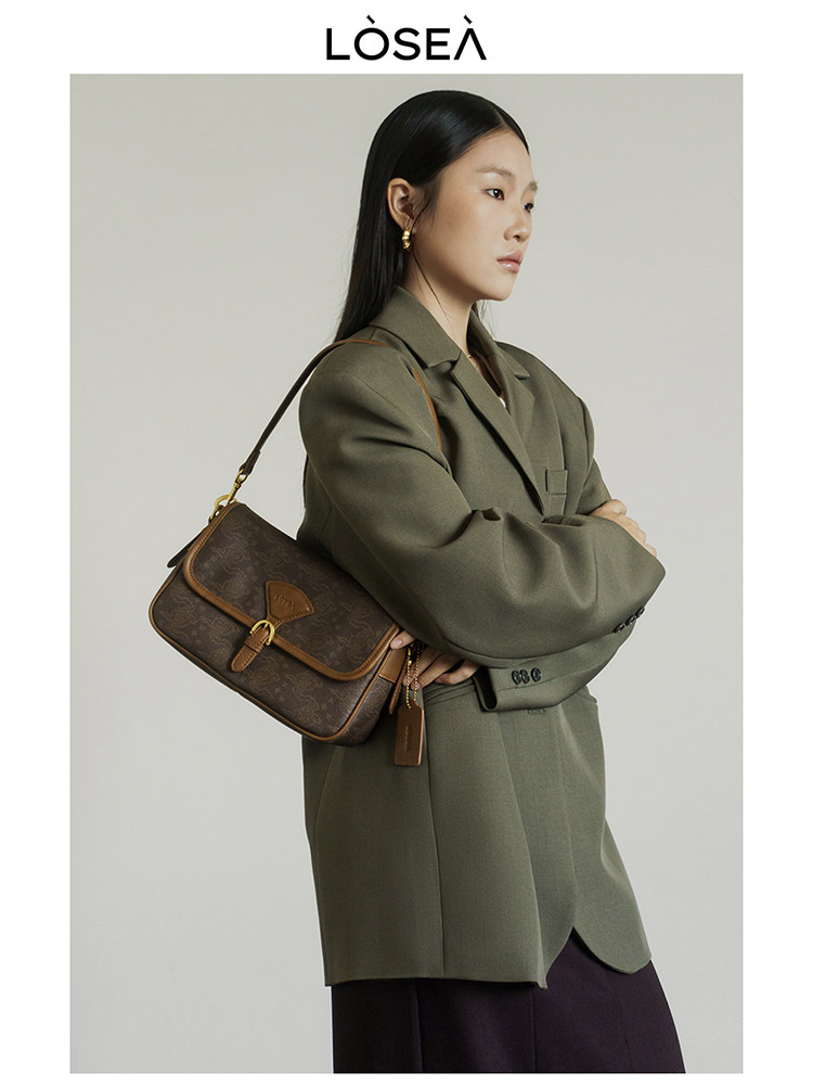 Brown monogram shoulder bag worn by a model in an olive blazer