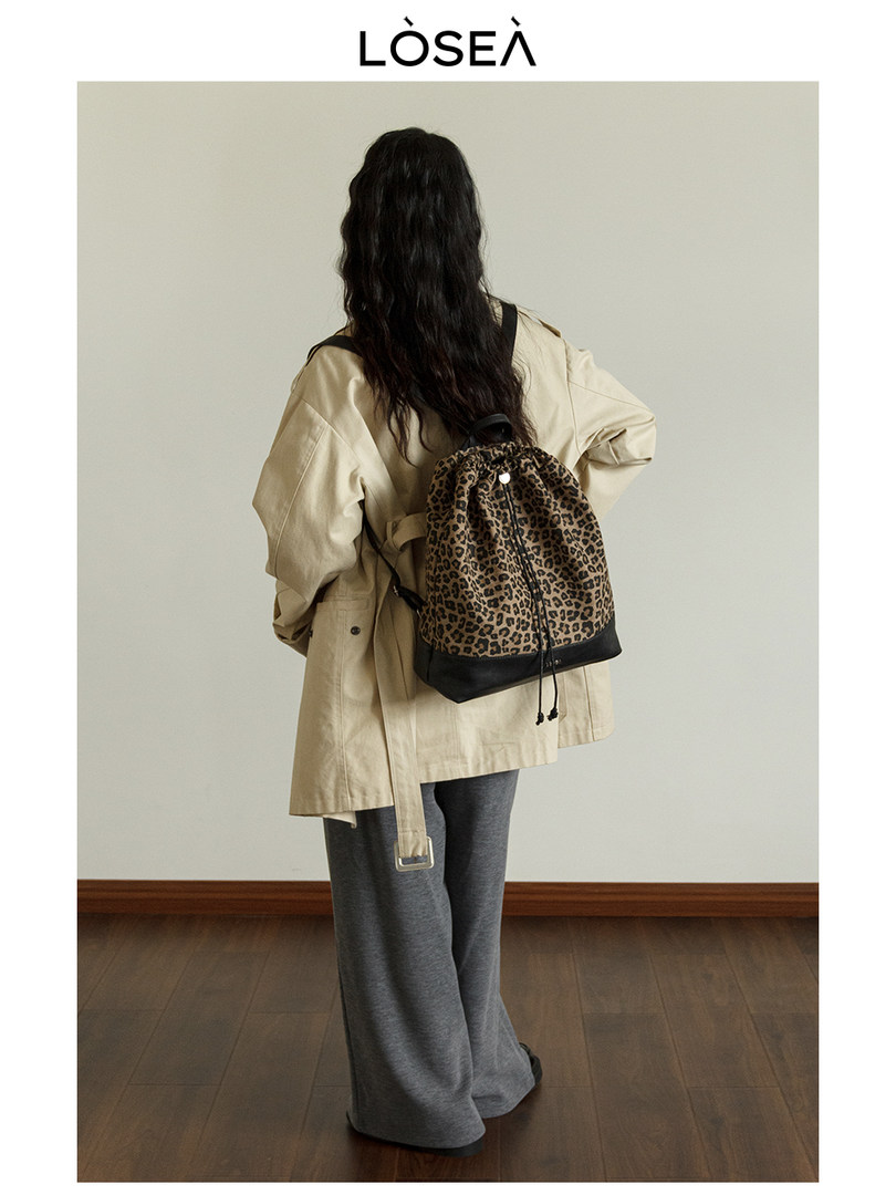 Model wearing a leopard print drawstring backpack with a beige trench coat