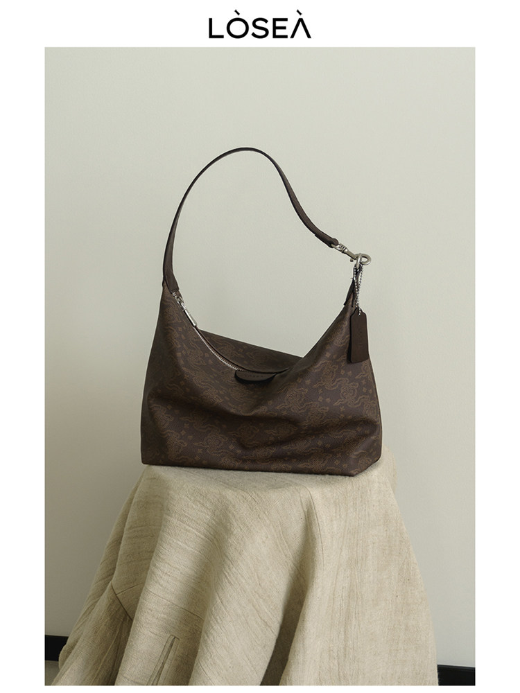 Brown shoulder handbag displayed on a stool