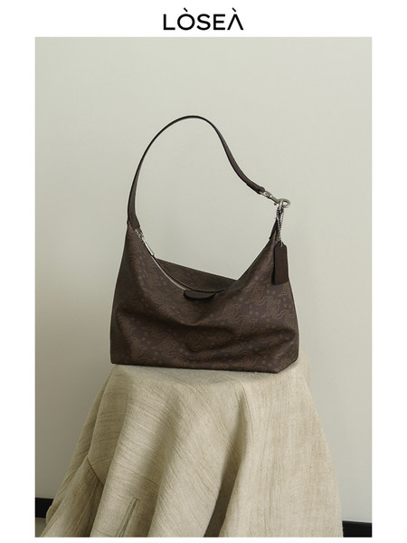 Brown shoulder handbag displayed on a stool