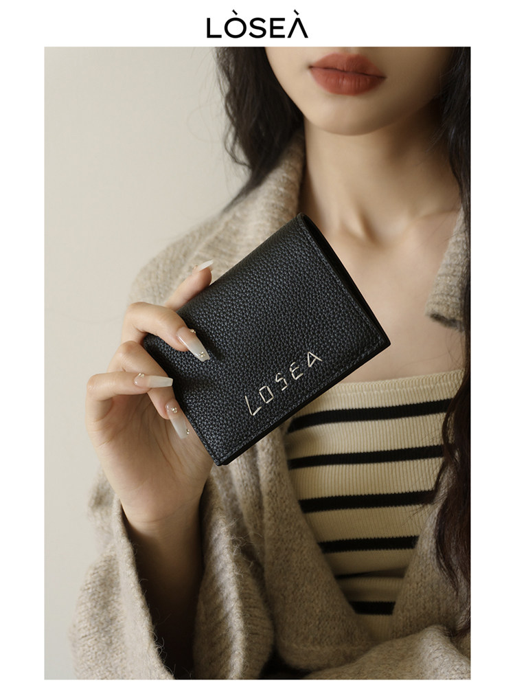 Black textured wallet held by a model