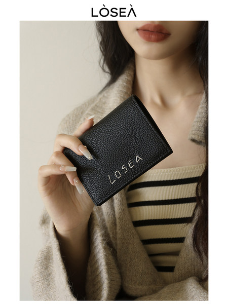 Black textured wallet held by a model
