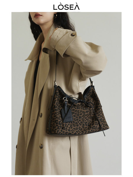 Model wearing a beige trench coat with a leopard print shoulder bag