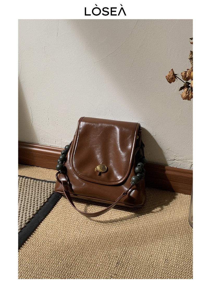 Brown leather handbag with bead strap displayed indoors