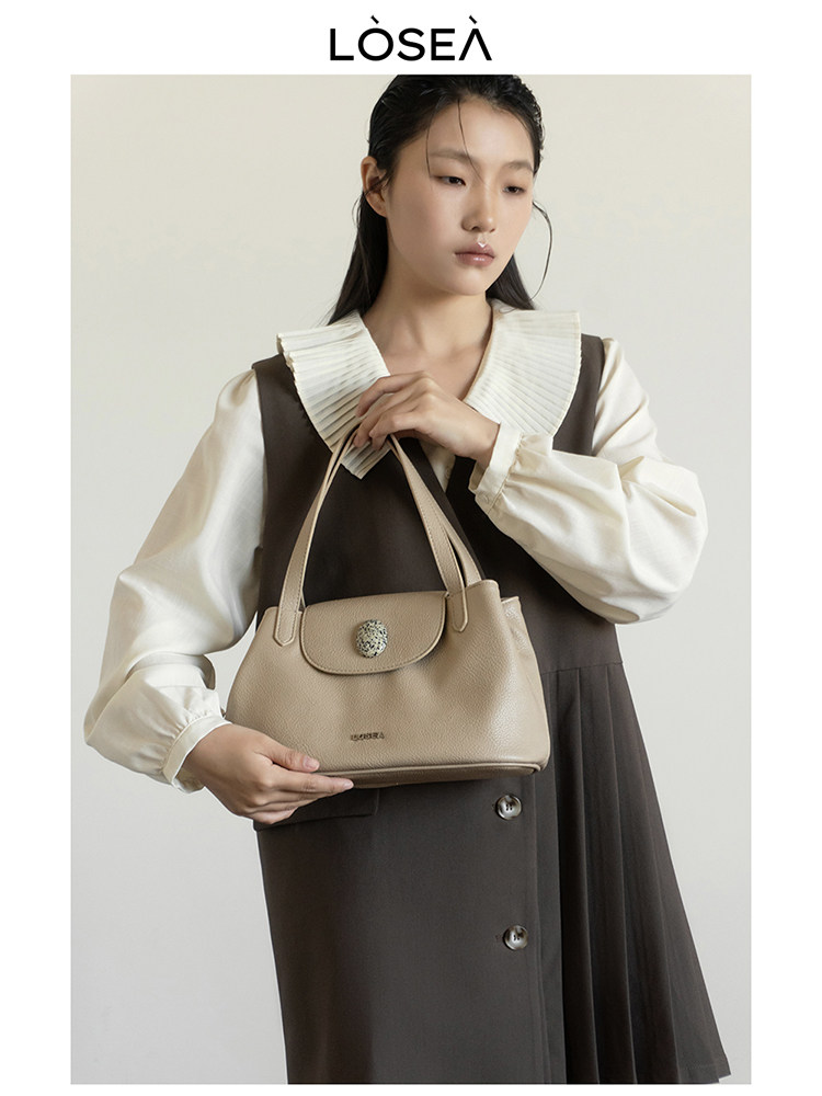 Beige leather handbag held by a model