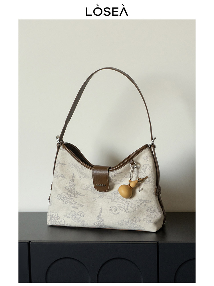 Beige patterned shoulder handbag with brown trim and long strap