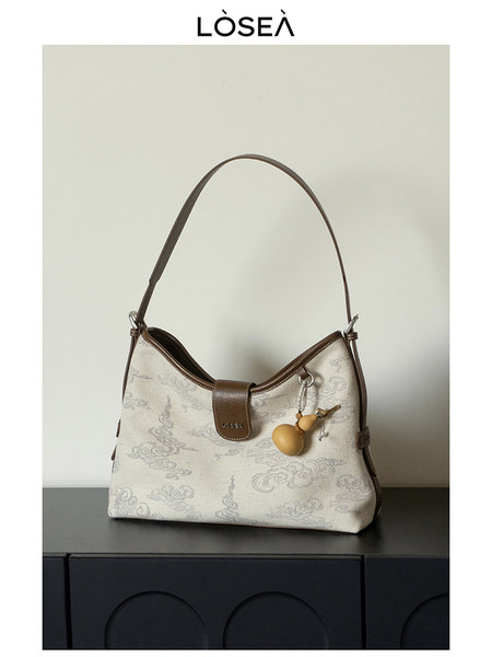 Beige patterned shoulder handbag with brown trim and long strap